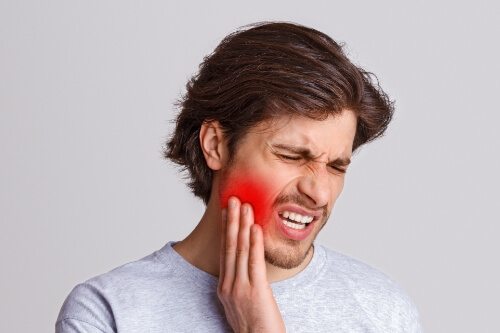 Man wincing and holding his cheek in pain