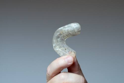Hand holding a white nightguard for bruxism