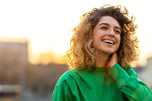 Young woman in green sweater smiling outdoors