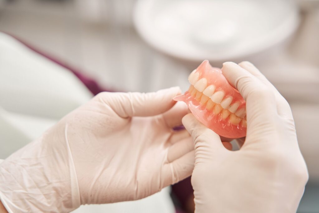 Hands in white gloves holding full dentures